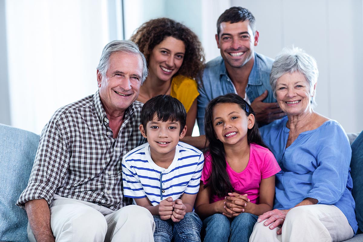 Portrait of happy family sitting together on sofa at home